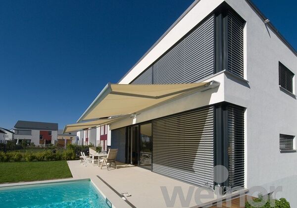 Modernes Einfamilienhaus mit Terrasse, Markise, Pool und Sonnenschutz an den Fenstern.