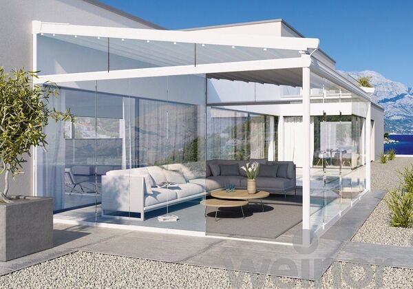 Moderne Terrasse mit Glasüberdachung, stilvollen Loungemöbeln und Meerblick bei Sonnenschein.