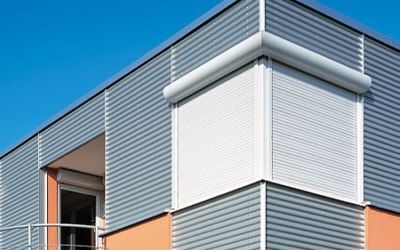 Modernes Gebäude mit Außenjalousien und Rollläden als Sonnenschutz an Fenstern.